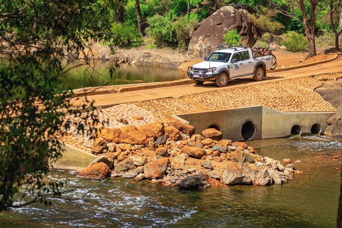 Ute driving across low lying bridge