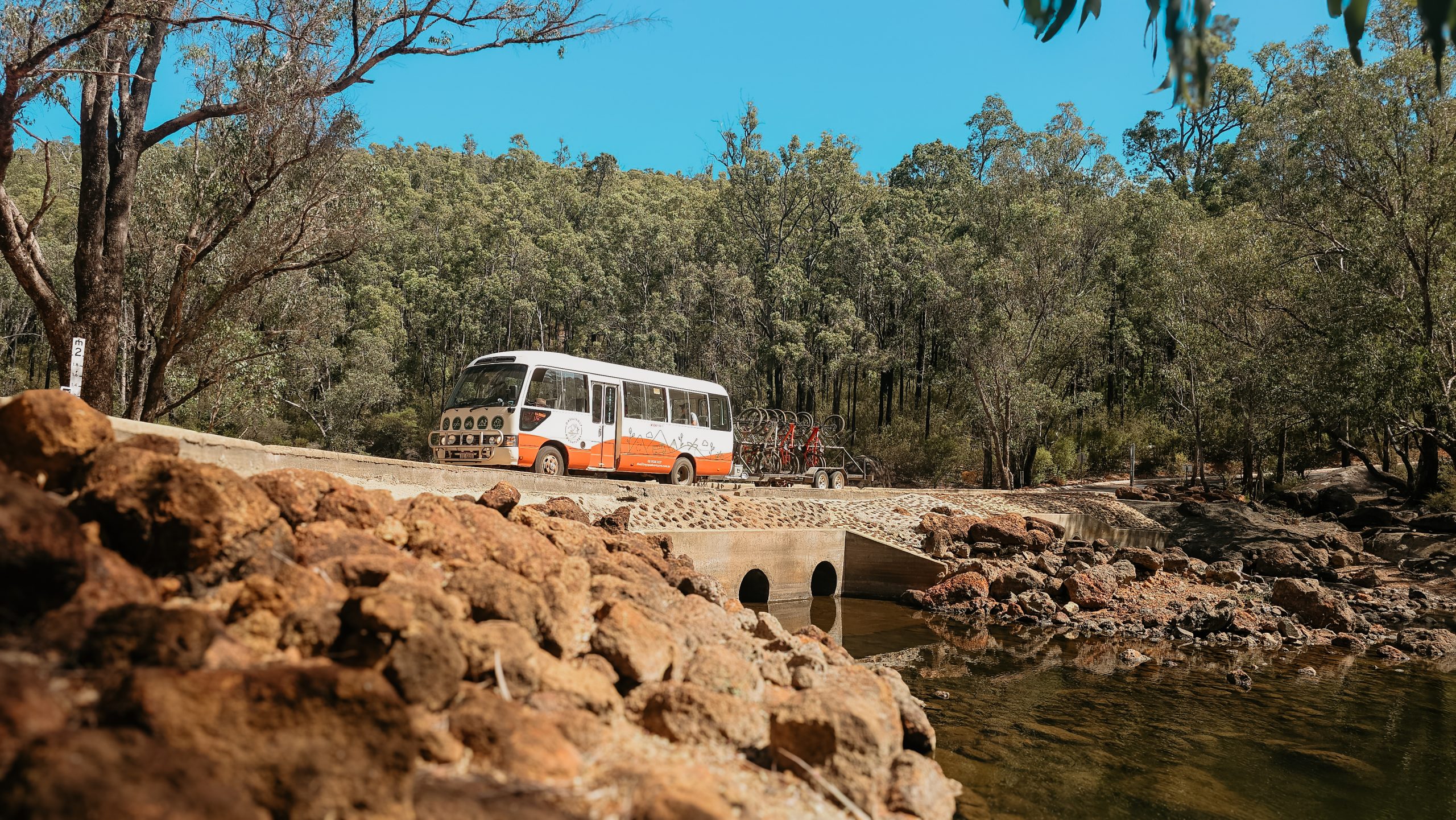 Dwellingup Adventures charter bus driving over rocky river crossing